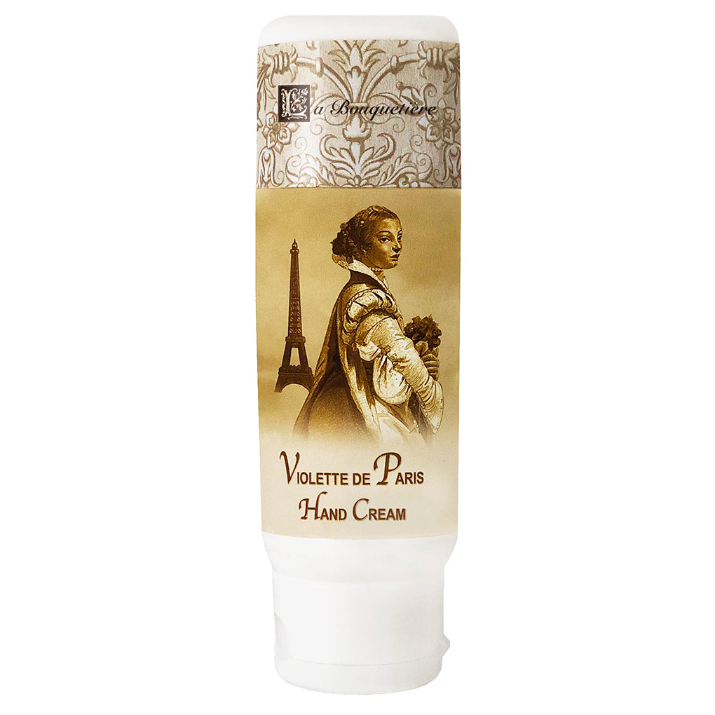 A tube of La Bouquetiere Violette de Paris hand cream featuring a vintage-style illustration of a woman holding flowers, with the Eiffel Tower in the background, now infused with organic shea butter.