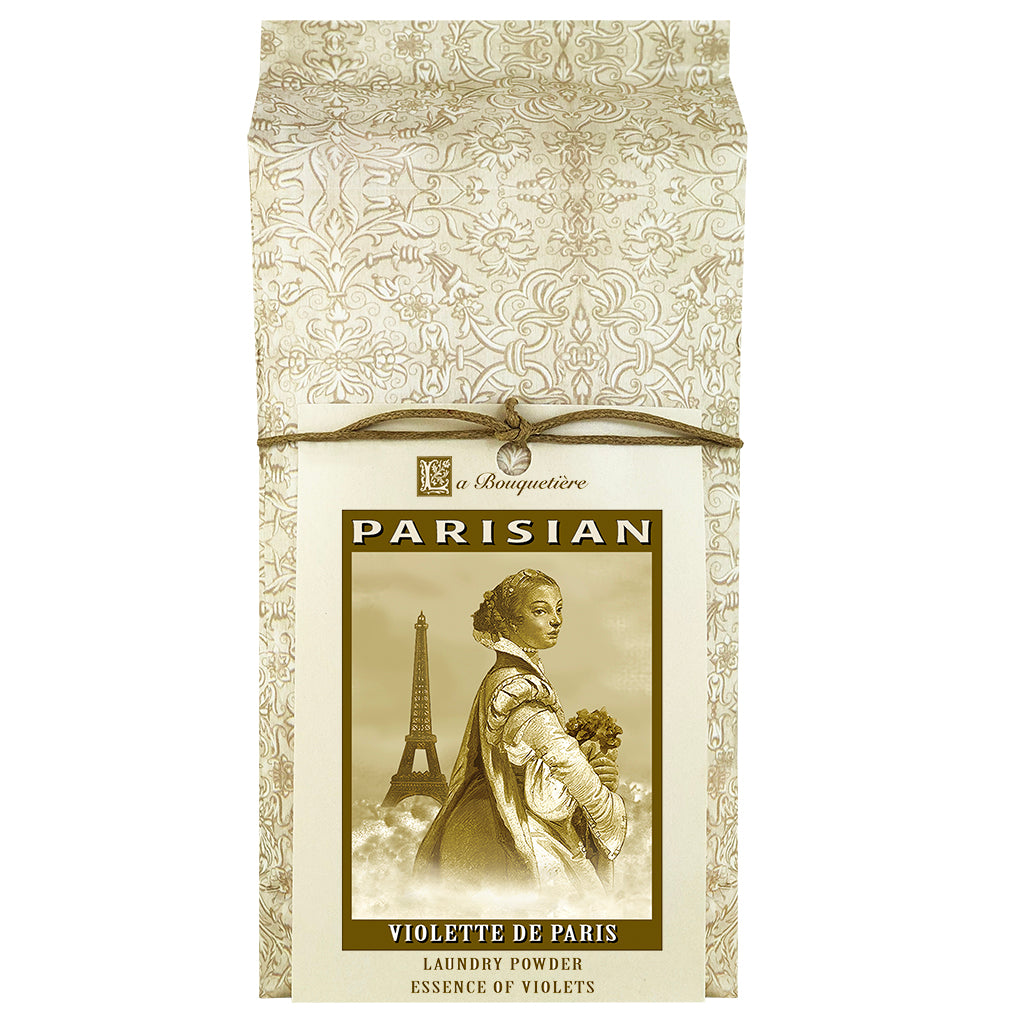 Elegant package of "La Bouquetiere Violette de Paris" biodegradable laundry powder featuring vintage style artwork of a woman and the eiffel tower, decorated in a floral beige and white