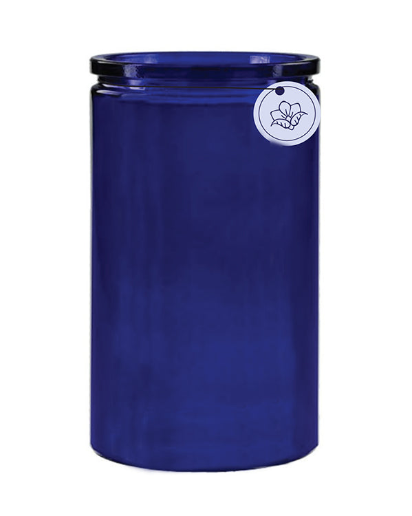A vibrant cobalt blue cylindrical ceramic vase with a glossy finish, featuring a small round white label with a floral design hanging from the rim and containing U.S. Apothecary Violet + Yarrow Candle soy and vegetable wax.
