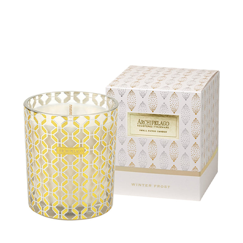 A decorative Archipelago Winter Frost Candle in a glass holder with a gold geometric pattern, displayed next to its matching patterned box labeled "Archipelago Winter Frost.