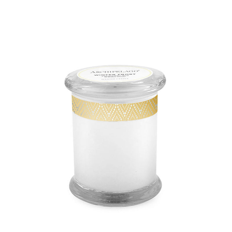 A cylindrical glass candle jar with a white label and a golden geometric pattern around the center. The lid has a label that says "Archipelago Winter Frost Glass Jar Candle" with additional text.