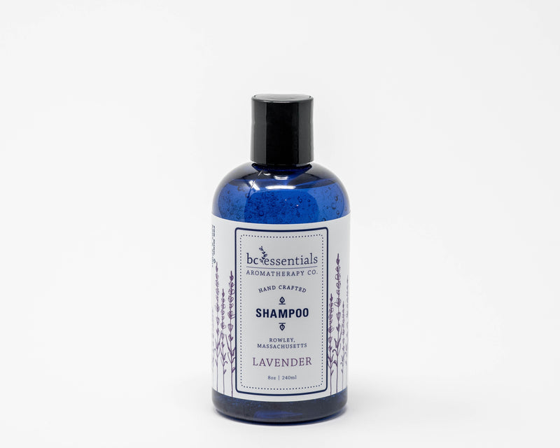 A transparent bottle of BC Essentials Lavender Shampoo with blue contents, labeled "BC Essentials aromatherapy co. hand crafted, moisturizes & nourishes, lavender," on a plain white background.