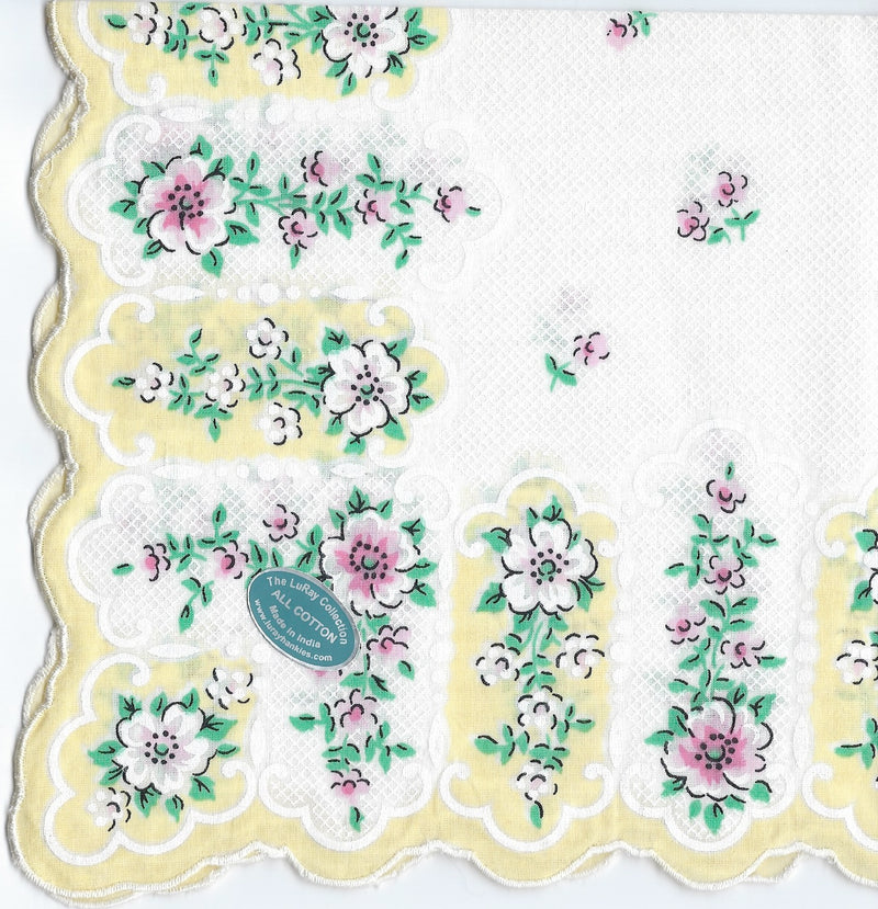 A detailed image of a Vintage-Inspired Hanky from Hankies ala Carte, with a scalloped edge, featuring intricate lace patterns and embroidered floral designs in shades of pink, green, and white.