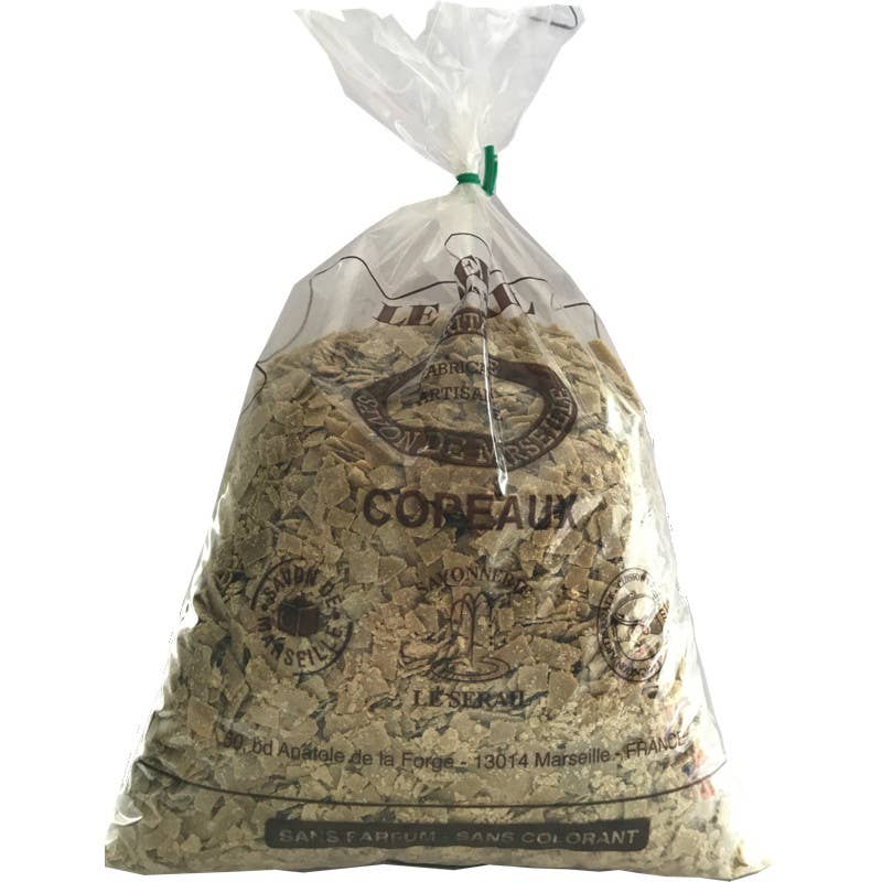 A transparent plastic bag full of beige, cube-shaped cork pieces, labeled in French for decoration or mulching uses, tied at the top with a white twist tie containing French Soaps Savon de Marseille Olive Soap Flakes.