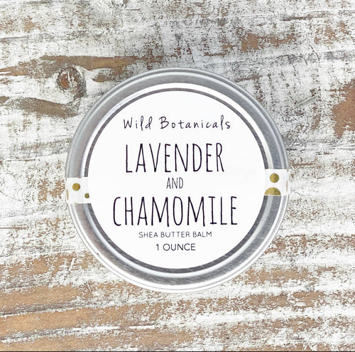 A top view of a round, 1-ounce container of Wild Botanicals - Lavender and Chamomile Shea Butter Cream with hemp seed oil, displayed on a rustic wooden surface.