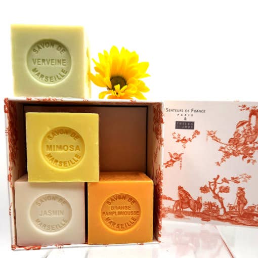 A collection of Senteurs De France Coffret of Jasmine, Lemon, Orange-grapefruit & Verbena Cube Soaps in various scents including verveine, mimosa, jasmin, and pamplemousse, packaged in a decorative box.