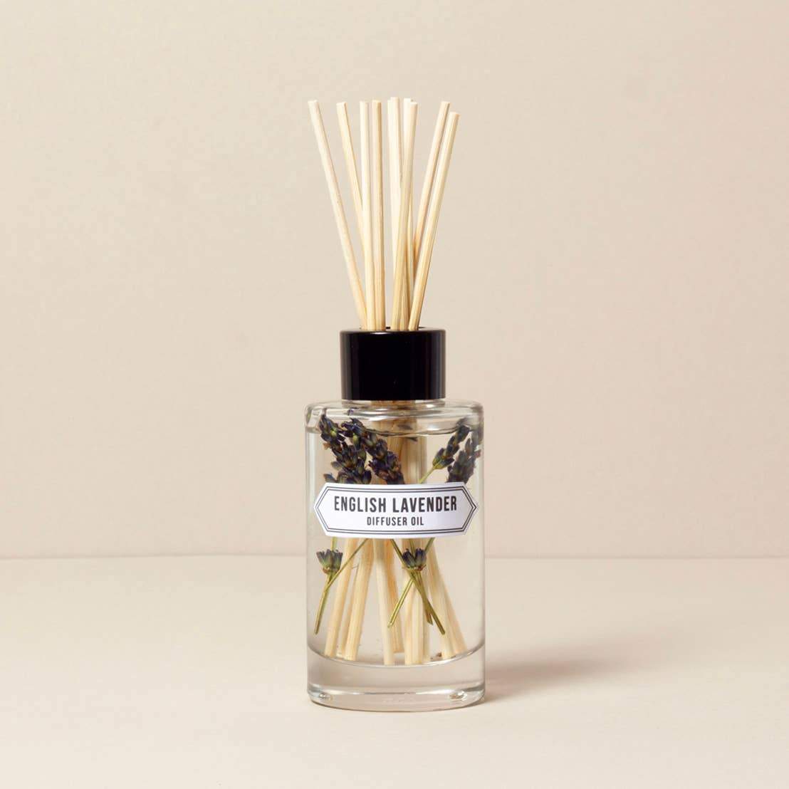 A clear glass diffuser bottle labeled "Norfolk Natural Living English Lavender Diffuser - 200ml" with dried lavender inside and several reed sticks, against a neutral background.