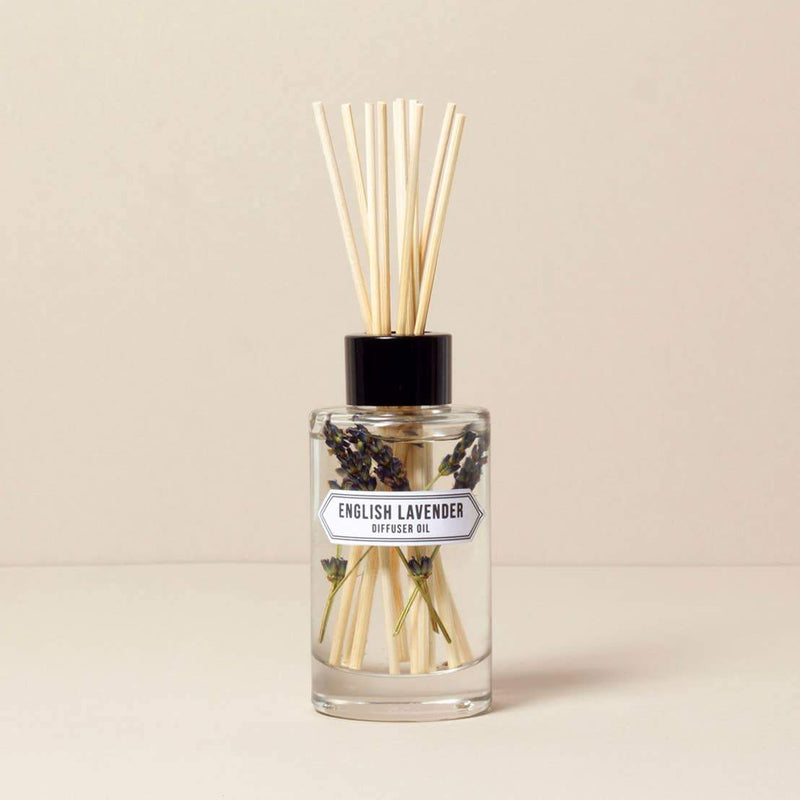 A reed diffuser bottle labeled "Norfolk Natural Living English Lavender Diffuser - 200ml" with several reed sticks inserted, set against a neutral background. Lavender sprigs are visible inside the clear glass bottle.