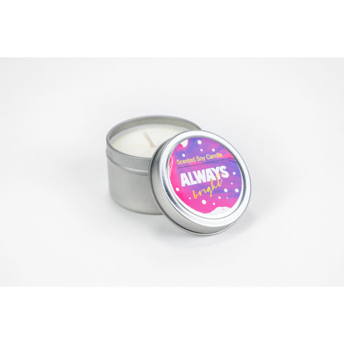 A small, open tin container with a Lizush Lavender Bergamot Candle inside. The lid, placed beside the candle, has a pink label that reads "always kind" in white letters with purple accents.