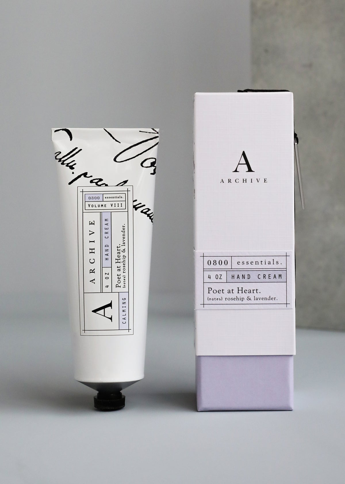 A tube of ARCHIVE by Margot Elena - Poet at Heart Hand Cream next to its box, set against a gray backdrop.