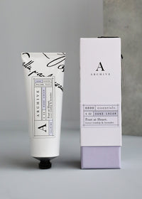 A tube of ARCHIVE by Margot Elena - Poet at Heart Hand Cream next to its box, set against a gray backdrop.