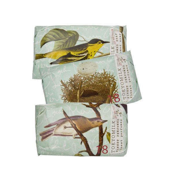 Three stacked bars of Margot Elena's TokyoMilk Audubon Mini-Soap Collection NO. 18 in decorative wrappers featuring bird illustrations, including a yellow bird and a nest with eggs, set against a light script background.