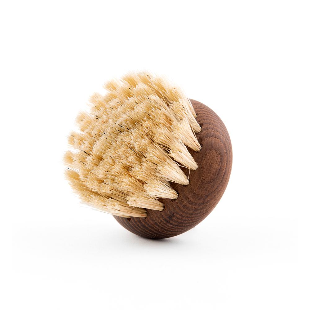 A round, wooden Andrée Jardin Heritage Ash Wood Body Brush with stiff, natural bristles fanning out, photographed against a white background alongside Andrée Jardin vintage toiletries.