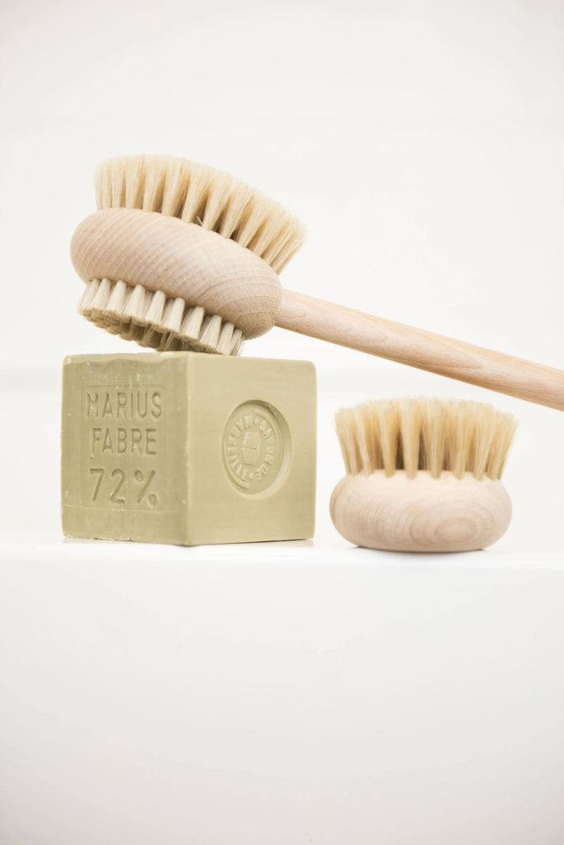 Two Andrée Jardin Beechwood Handle Bath & Body Brushes and a bar of soap labeled "marius fabre 72%" displayed against a white background. One brush is a French body brush.