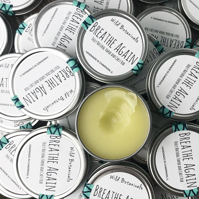 A close-up image displaying several open containers of Wild Botanicals Eucalyptus Breathe Again chest rub with visible green natural salve, arranged neatly, showcasing their silver lids with product labels.