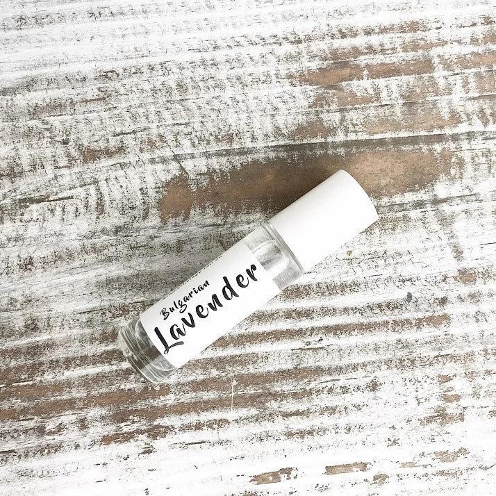 A small glass roll-on bottle labeled "Wild Botanicals Lavender" rests on a rustic wooden surface, highlighting a simple, clean design ideal for a scent or essential oil product.