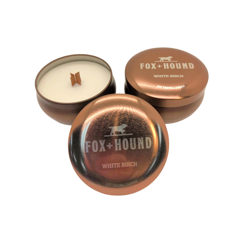Three Fox + Hound White Birch Odor Eliminator Travel Soy Candles 7 oz, with copper-toned lids. One candle is open, showing a white wax and a wooden wick, while the other two are closed, displaying the brand.