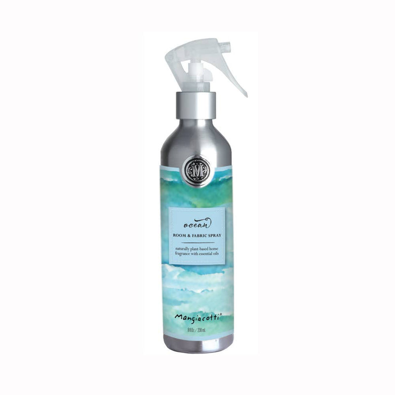 A silver spray bottle labeled "Mangiacotti - NEW! Ocean Room & Fabric Spray" from Mangiacotti, featuring a swirling turquoise and white design suggesting ocean waves, with a white spray nozzle on top.