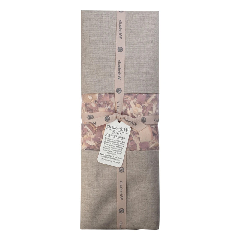 A neatly folded light brown towel with elizabeth W Cedar Linen Drawer Liner - Natural sheets and branded packaging bands displaying the text "elizabethW san francisco" and an attached label with product information.