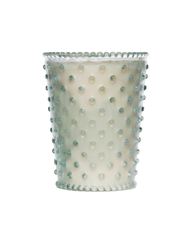 A decorative Simpatico NO. 96 Creme Fraiche Hobnail Glass Candle with a dotted pearl design and a turquoise rim, isolated on a white background, suitable for hand-poured candles.