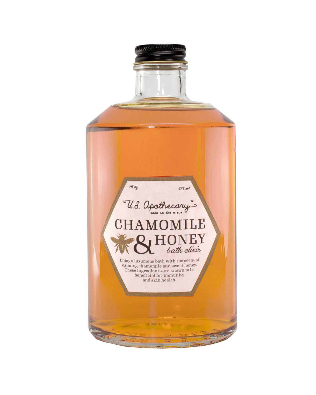 A clear glass bottle filled with amber-colored liquid, labeled "U.S. Apothecary Chamomile & Honey Bath Elixir," designed for a relaxing bath, against a white background.