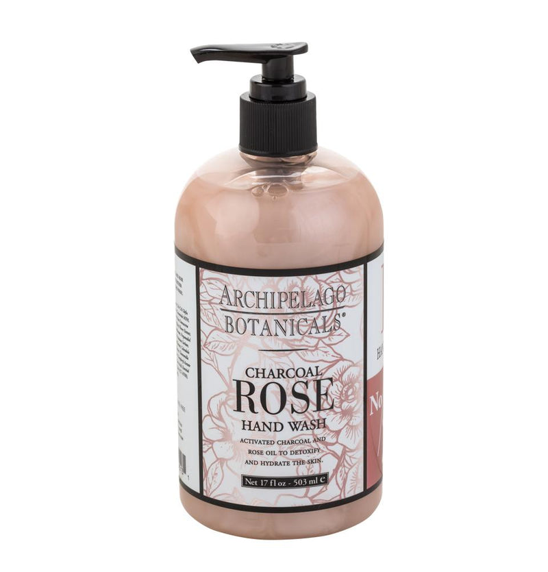 A bottle of Archipelago Botanicals Charcoal Rose Handwash 17oz with a black pump, labeled with pink and white floral designs, against a white background.