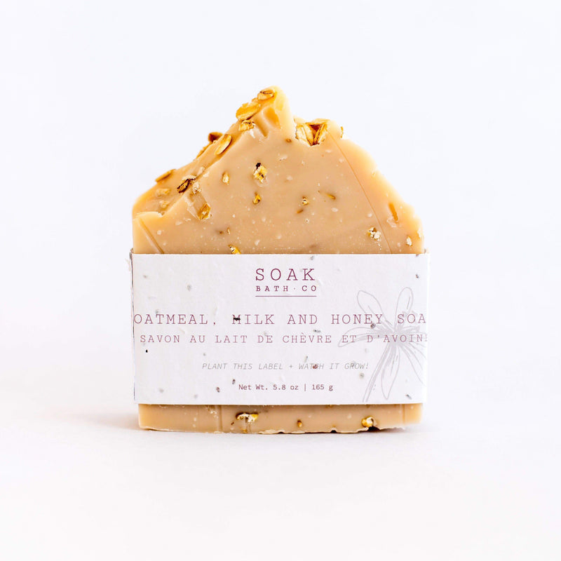 A bar of SOAK Bath Co. - Oatmeal Milk and Honey Soap, wrapped in a plantable label on a white background.
