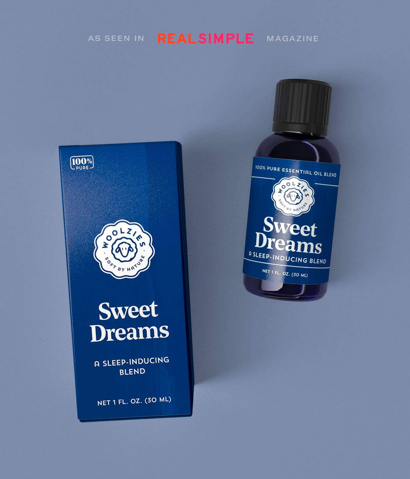 A product image featuring a bottle of "Woolzies Sweet Dreams Blend - 1oz" sleep-inducing essential oil next to its packaging, displayed against a gray background with a "Real Simple" magazine logo.