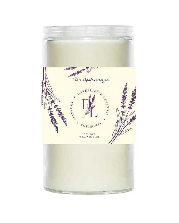 A U.S. Apothecary Dandelion & Lavender Candle in a transparent glass jar with a label featuring lavender and dandelion illustrations, and the text "dandelion & lavender" in elegant typography.