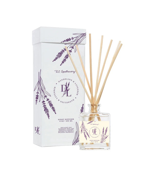 A U.S. Apothecary Dandelion & Lavender Scent Diffuser Kit with a glass bottle and several wooden sticks, alongside a white box with lavender plant illustrations and text detailing the product's brand and fragrance notes.