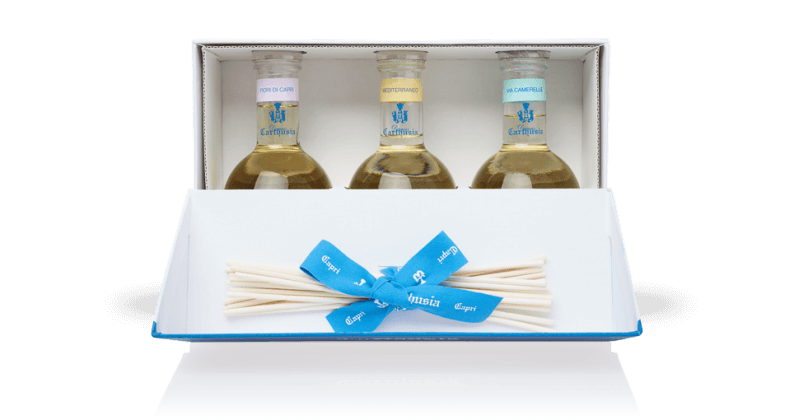 Set of three fragrance oils labeled "Carthusia Home Diffuser Set", "refreshing", and "citrus gifts" in small glass bottles, neatly packaged in a white box with a blue ribbon and a Carthusia I Profumi de Capri.