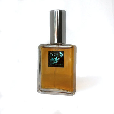 A square glass perfume bottle with a silver cap, filled with amber-colored liquid. The label features a teal logo with the text "DSH Perfumes" and hints of gourmand fragrance. DSH Eau de Parfum - Bourbon Vanilla by Dawn Spencer Hurwitz Perfumer.