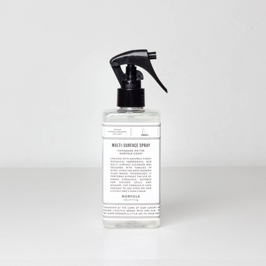 A transparent spray bottle with a black spray nozzle labeled as "Norfolk Natural Living Coastal Multi Surface Cleaner 300ml" against a plain white background. The label contains text with product details.