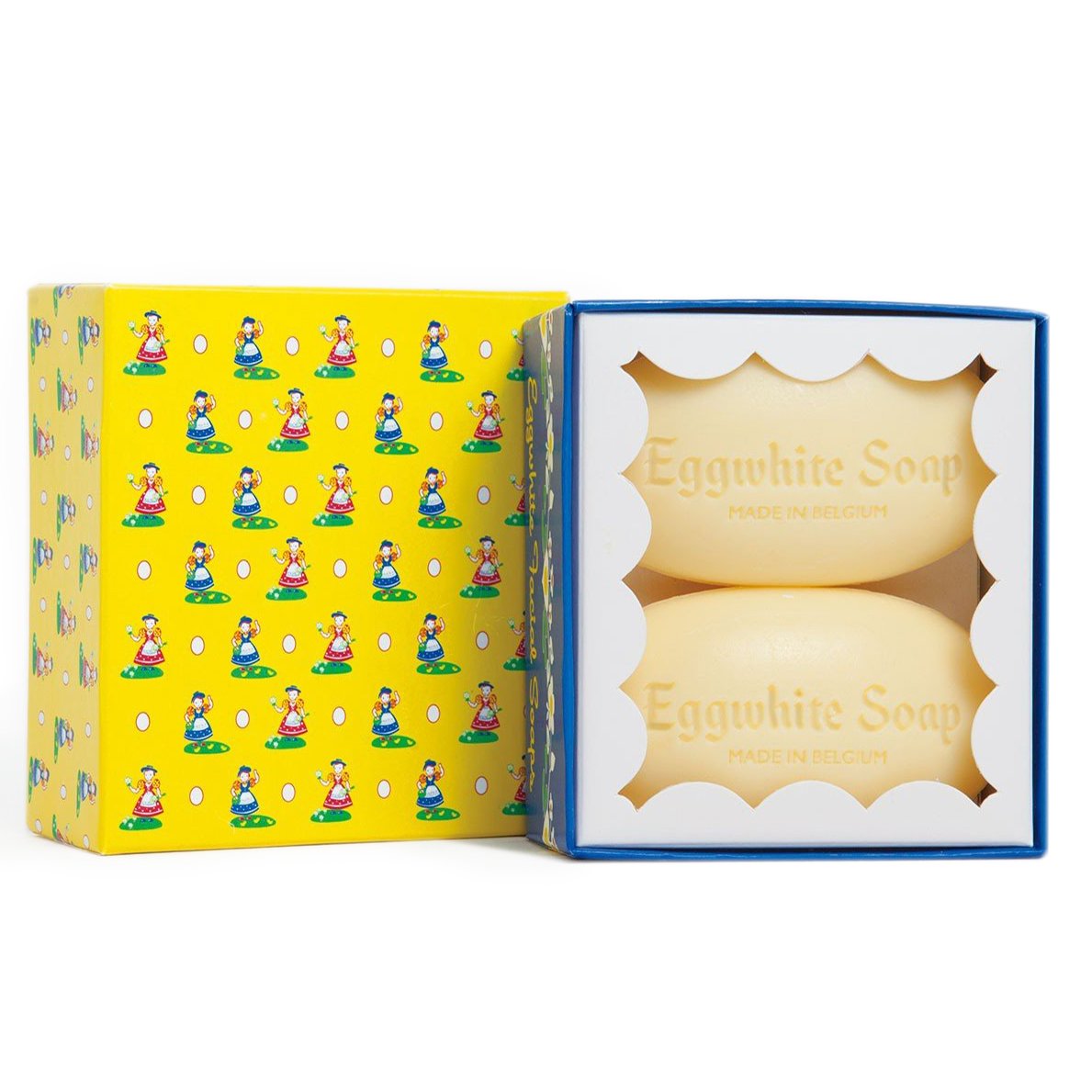 The image shows a box of Eggwhite Facial Mask 2 bar Gift Box made in Belgium by Soaps, Soaks & Pampering Products From Around the World. The box is yellow and blue with a pattern of women wearing bonnets and aprons. The opening displays two oval-shaped soap bars, perfect for adding a youthful glow to your skincare routine. The text on the soap reads "Eggwhite Soap Made in Belgium.