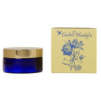 A Caswell Massey Elixir of Love Body Cream in a dark blue jar paired with a beige box adorned with blue floral artwork.