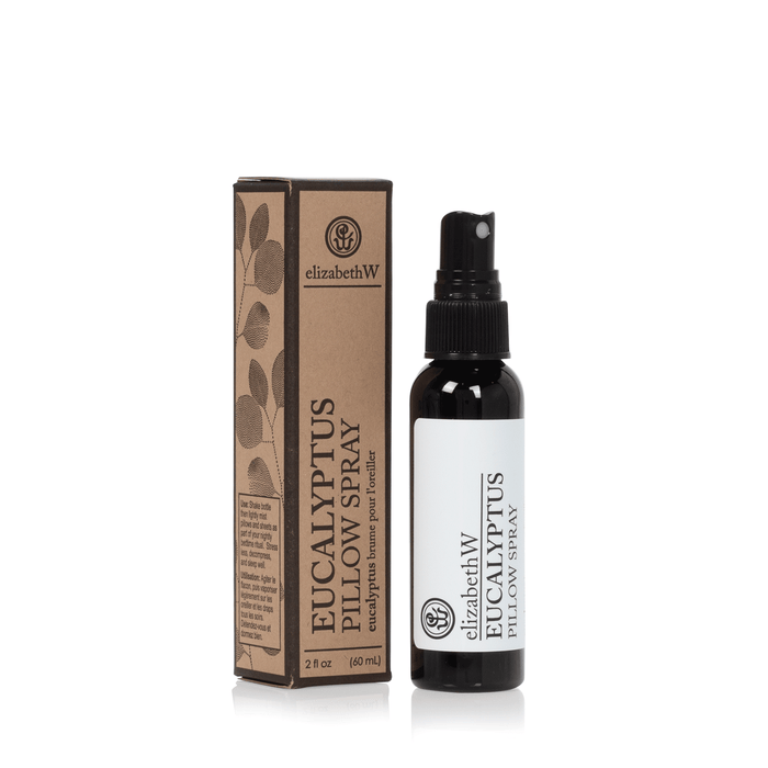 A bottle of elizabeth W Purely Essential Eucalyptus Pillow Spray next to its brown packaging box with leaf designs, displayed on a white background.