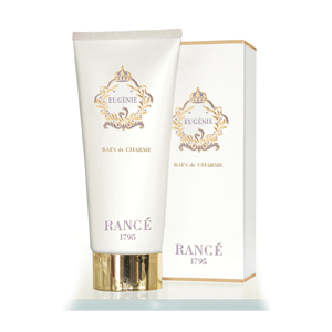 A tube of amber-scented Rance Eugenie Bath & Shower Gel by Rancé, positioned next to its elegant, white and gold packaging box displaying matching design elements.