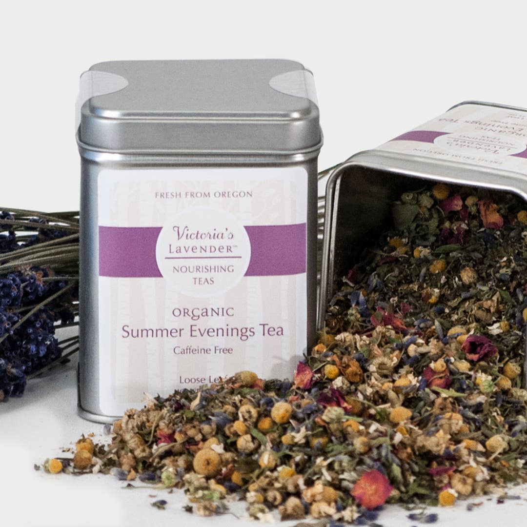 Two tins of Victoria's Lavender Organic Loose Leaf Herbal Tea – Summer Evenings, one open, displaying loose leaf herbal blend with flowers and herbs, alongside dried lavender sprigs.