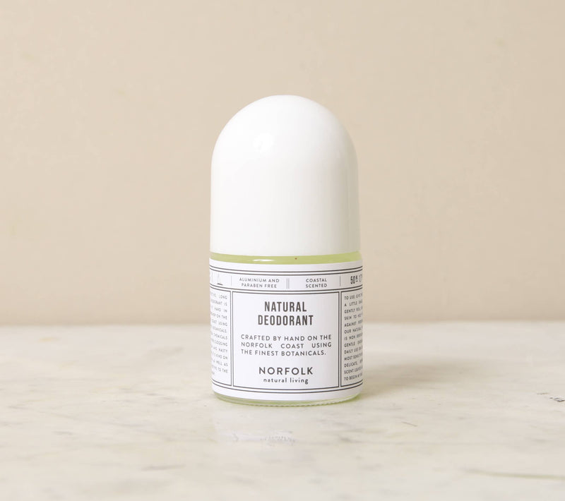 A white roll-on Norfolk Natural Living Coastal Natural Deodorant container labeled "aluminium free natural deodorant, Norfolk Natural Living" on a light beige background.