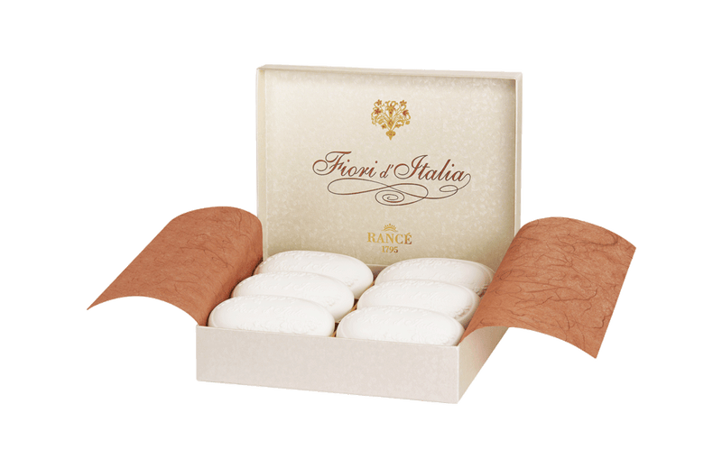 An open handmade box of four white, round Rancé Classic Soap - Fiori d' Italia soaps, displayed against a white background with the box's lid showcasing elegant, gold-accented Rancé branding.