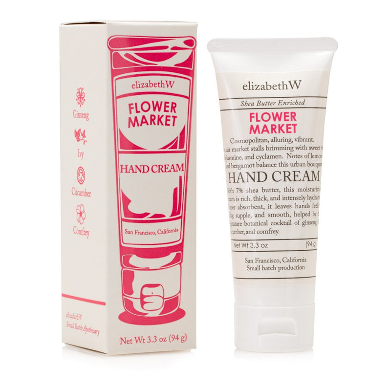 A product image showing a tube of elizabeth W Small Batch Apothecary Flower Market hand cream and its packaging. The packaging is pink with white and black text and decorative icons.