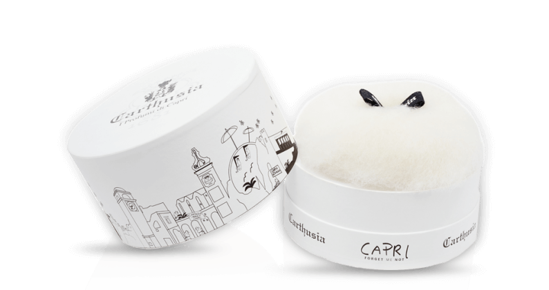 A round white box with black cityscape line art and "Carthusia I Profumi di Capri" and "Capri" on the lid holds fluffy dusting powder in Forget Me Not scent—luxury from Carthusia Capri Forget Me Not Dusting Powder.