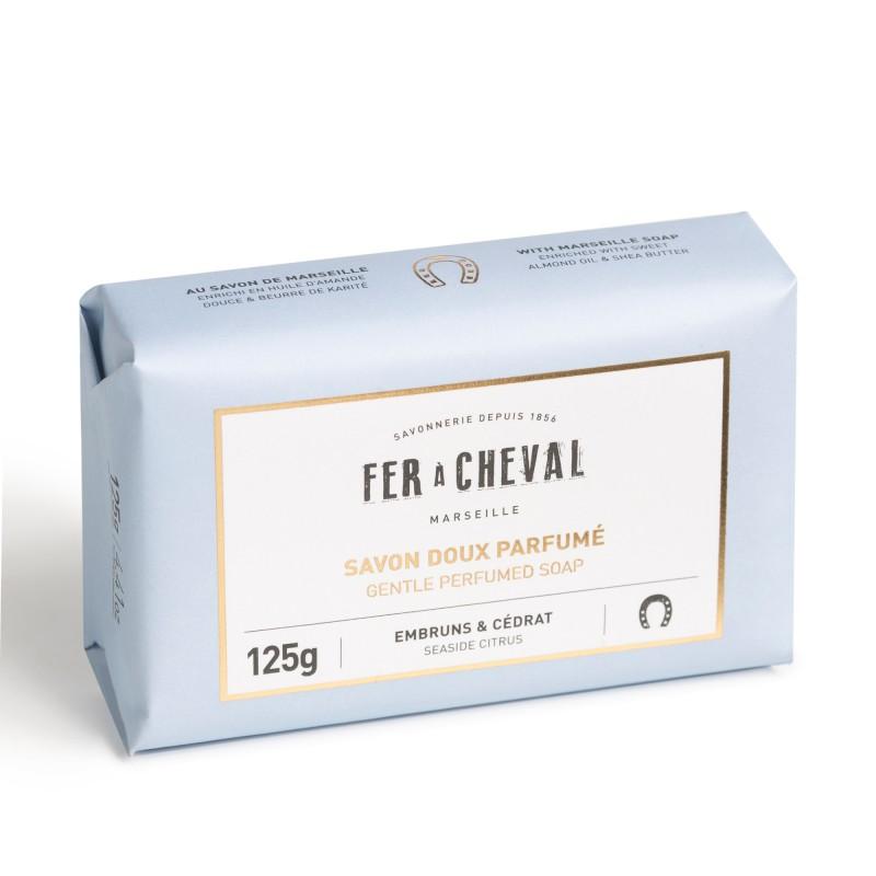 A packaged bar of Fer à Cheval Gentle Perfumed Soap Bar - Seaside Citrus 125g labeled in French, weighing 125 grams, with notes of emburns and cedrat. The package is light blue with elegant white and gold text.