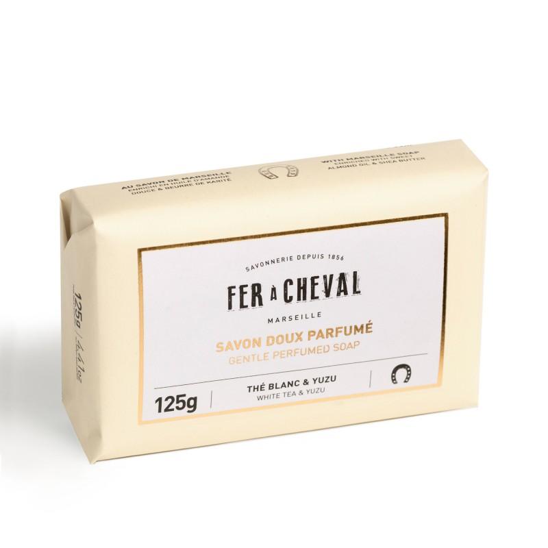 A bar of Fer à Cheval Gentle Perfumed Soap Bar - White Tea & Yuzu 125gm in beige packaging with black and green text, labeled "gentle perfumed soap white tea & yuzu", weighing 125g.