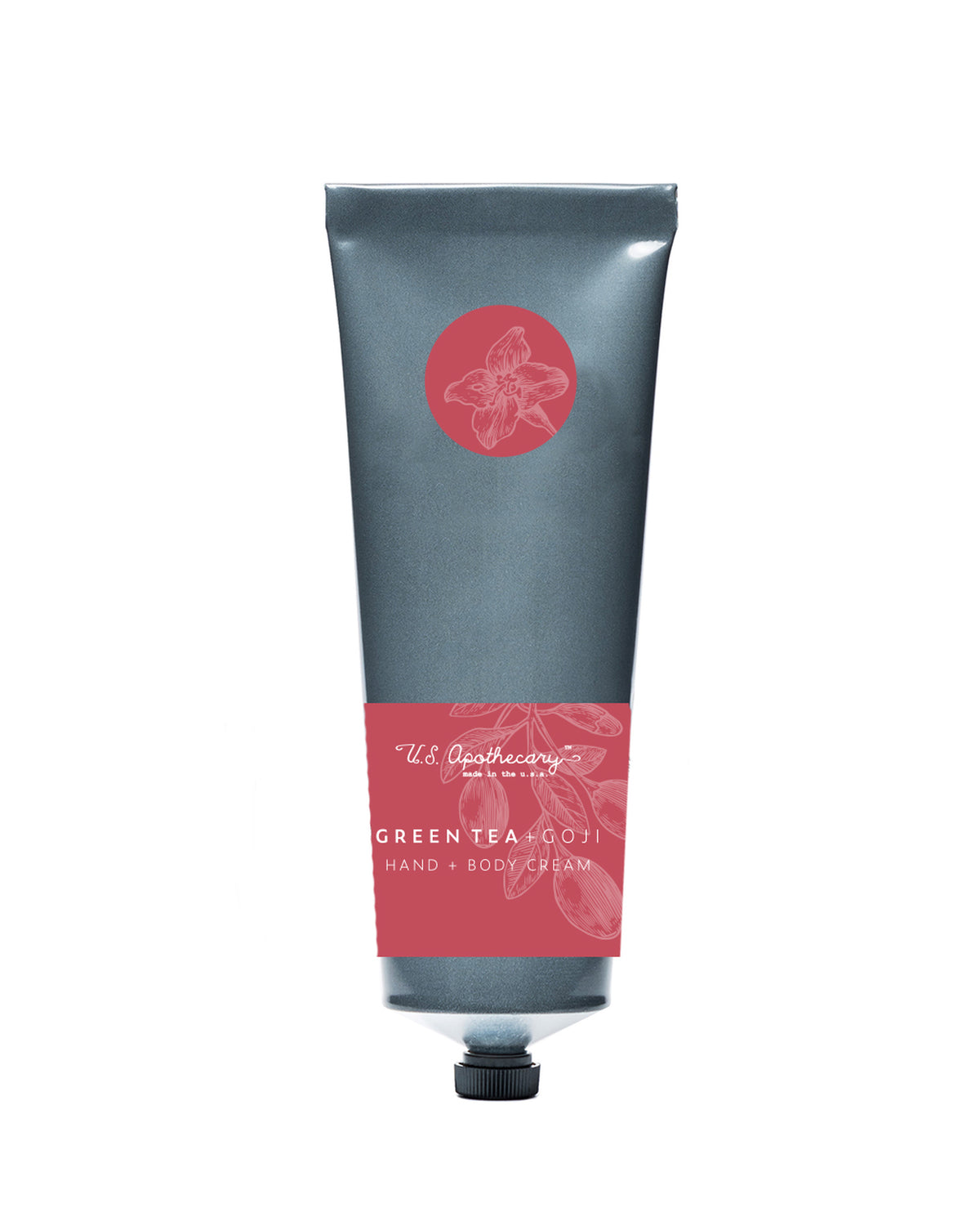 A tube of U.S. Apothecary Green Tea + Goji Berry hand and body cream labeled in elegant script on a sleek, gray background with a pink and red decorated label featuring botanical artwork.