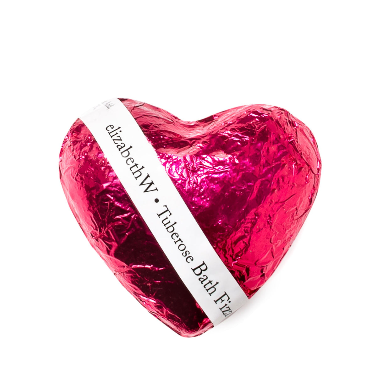 A shiny pink foil-wrapped heart-shaped elizabeth W Fizz Heart - Tuberose with a white label that reads "elizabethW tuberose bath fizzy." The background is pure white, emphasizing the product.