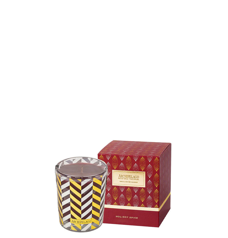 An Archipelago Botanicals Holiday Spice Boxed Votive Candle with a gold and white striped design next to its red box featuring gold patterns, labeled "archipelago holiday spice with ground cinnamon bark.
