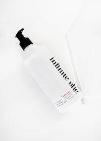 A minimalist Infinite She Fearless Hydrating Body Lotion bottle with a black pump and labeled "infinite style," infused with Shea Butter, against a white background. Brand Name: Margot Elena.