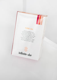 A white "Infinite She Vibrant Eau de Parfum" box by Margot Elena with text and logo, set against a simple white background. The box emphasizes a message of empowerment and freshness, featuring hints of Japanese Yuzu.