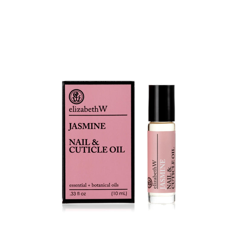 A bottle of elizabeth W Botanical Apothecary Jasmine Nail & Cuticle Oil next to its packaging. The label is pink with white text. The bottle is transparent, showing the light pink nourishing botanical oils inside.